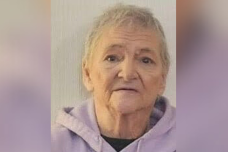 Photo of Debra Fox, an elderly White woman with cropped gray hair, wearing a light purple hooded sweatshirt